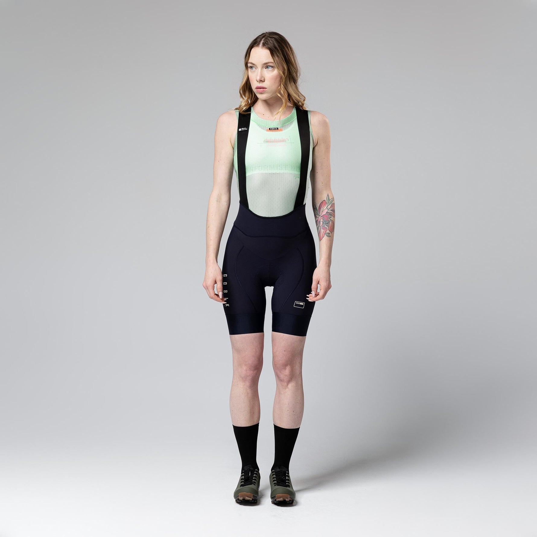 Woman wearing Gobik Matt bib shorts in ultrablue navy color with professional studio lighting