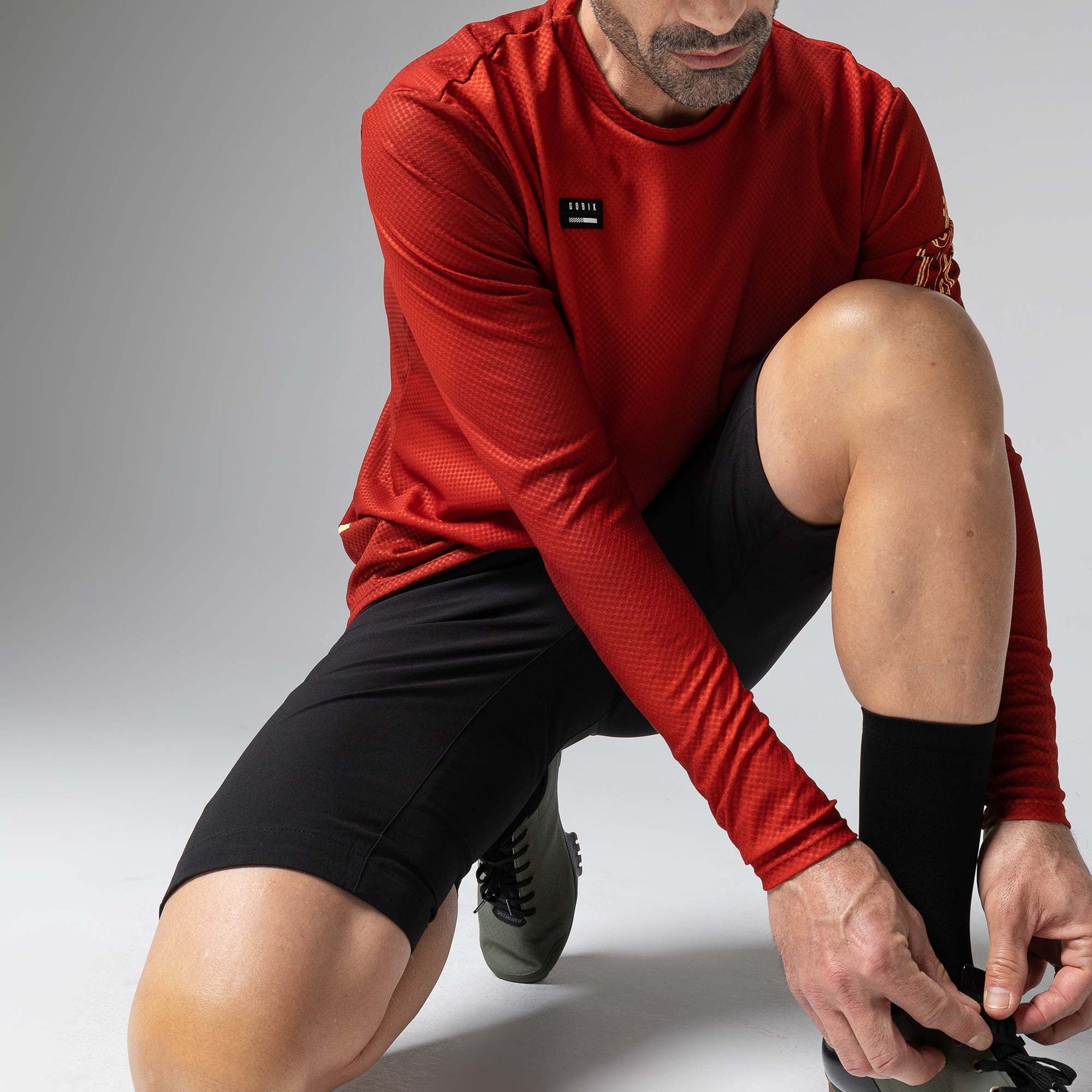 Man wearing red Gobik Terrain long sleeve athletic shirt in dynamic pose