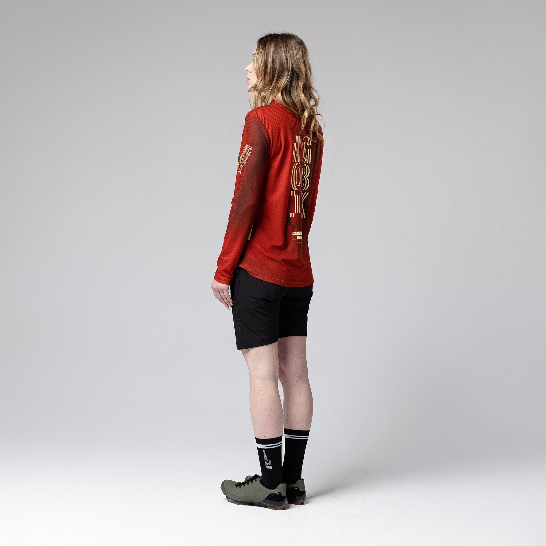 Woman wearing red Gobik Terrain long sleeve cycling shirt with black shorts