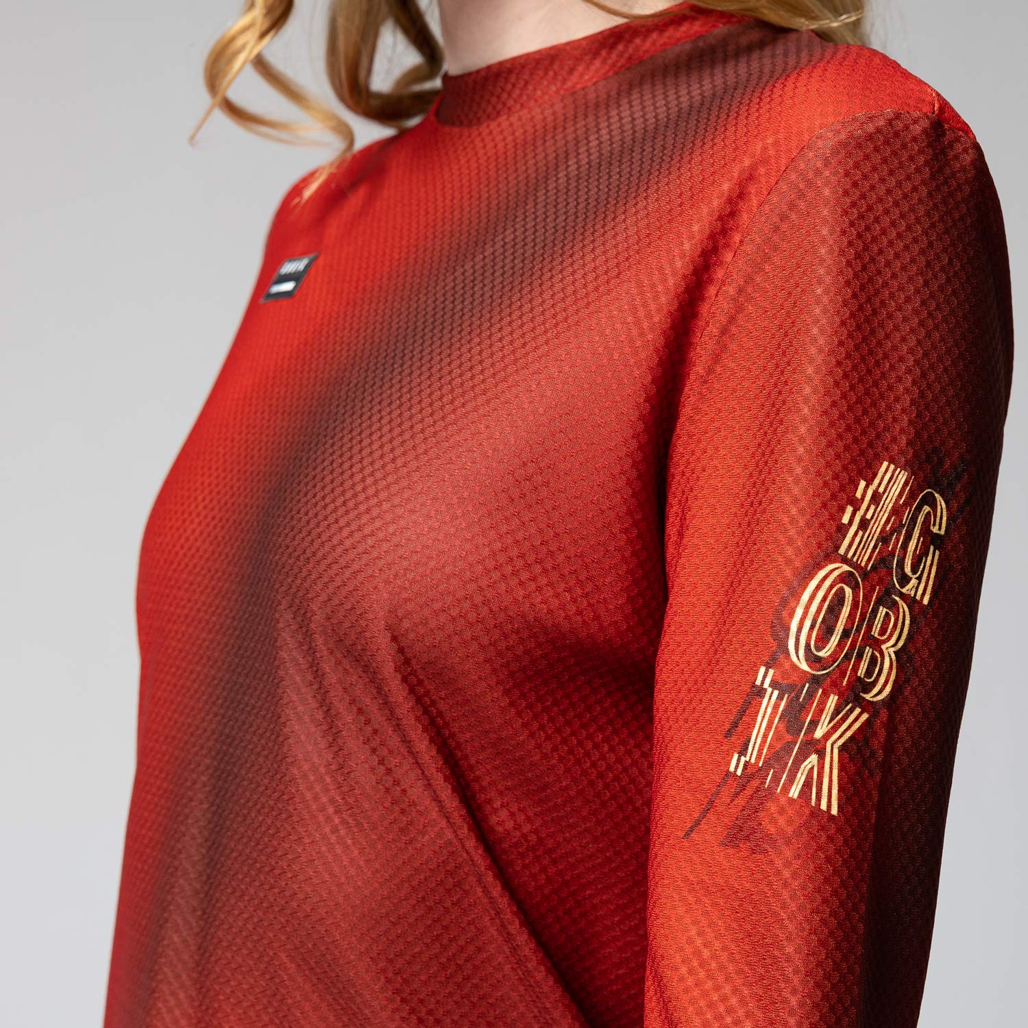 Woman wearing red Gobik Terrain long sleeve athletic shirt with textured fabric pattern