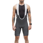 Man wearing grey Legg Plus bibshorts with white suspenders and black mesh tank top