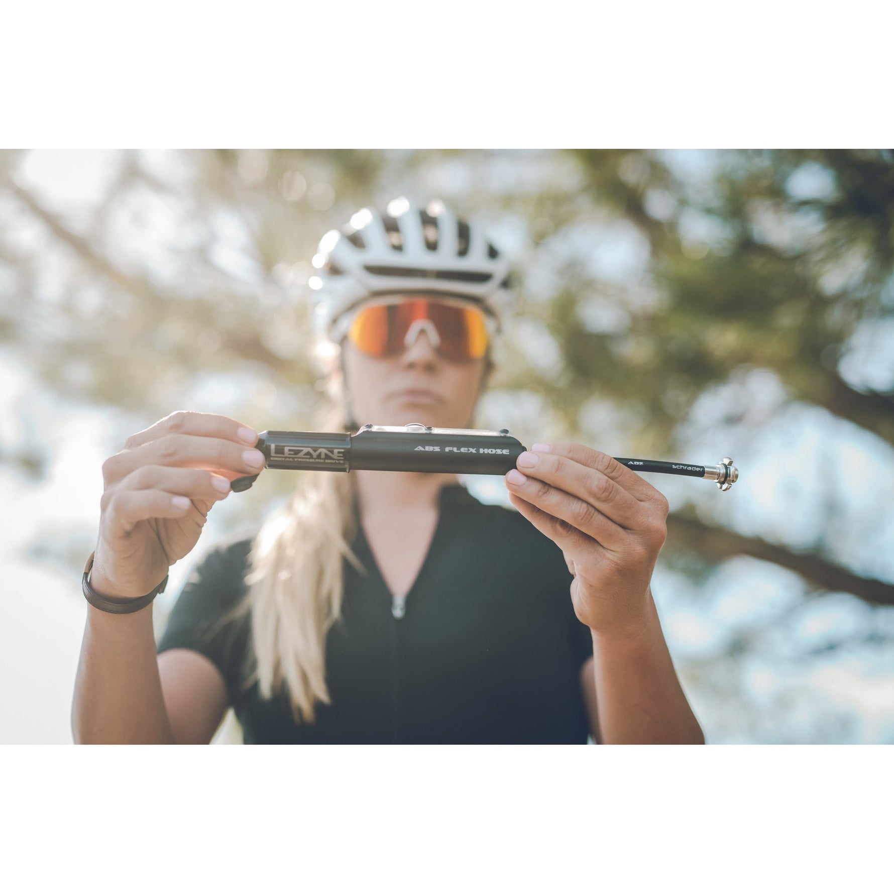 Cyclist holding Lezyne black digital pressure drive pump outdoors
