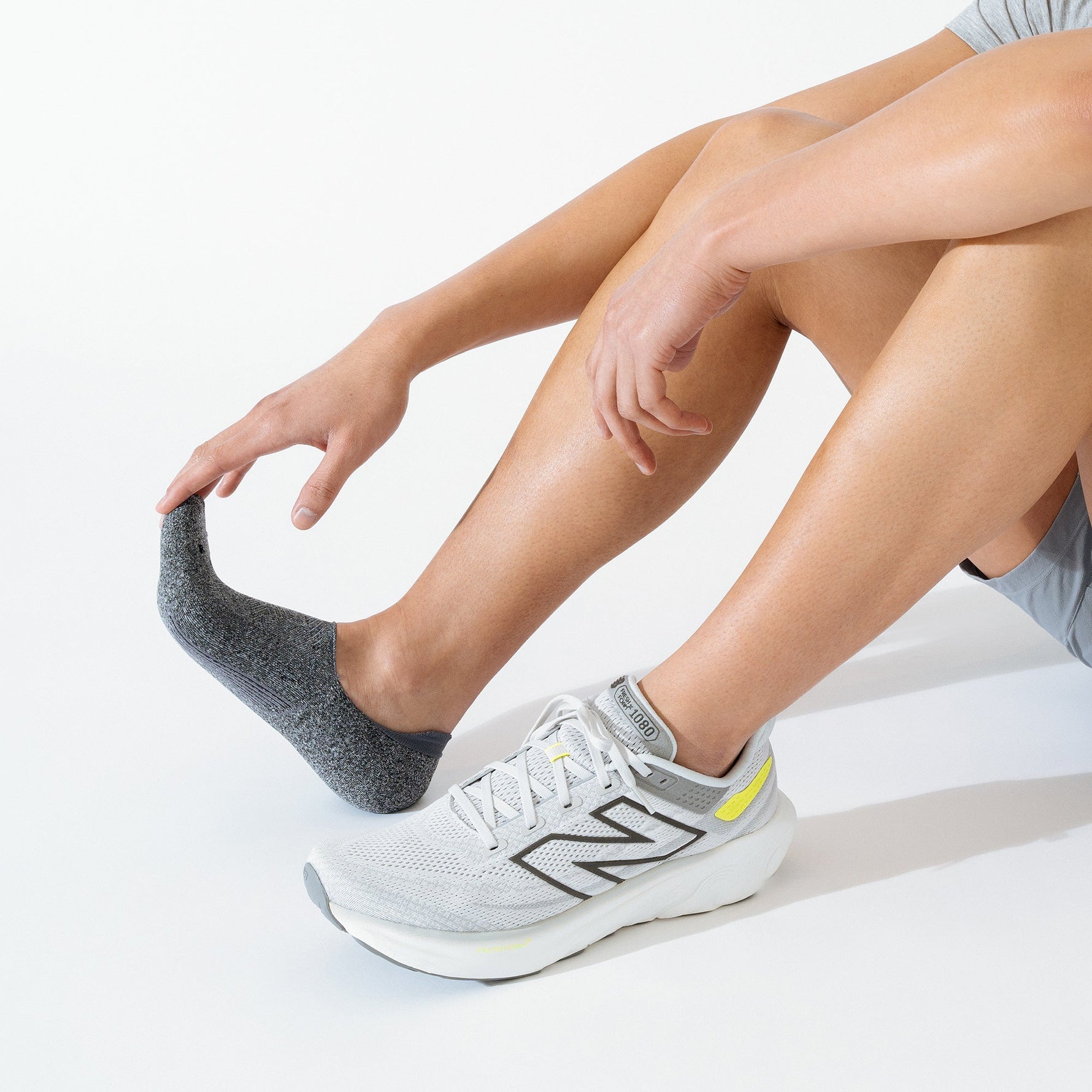 Person wearing gray Feetures Elite invisible socks with white running shoes