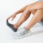 Person wearing Feetures Elite Light Cushion Invisible no-show socks in charcoal black with New Balance shoes