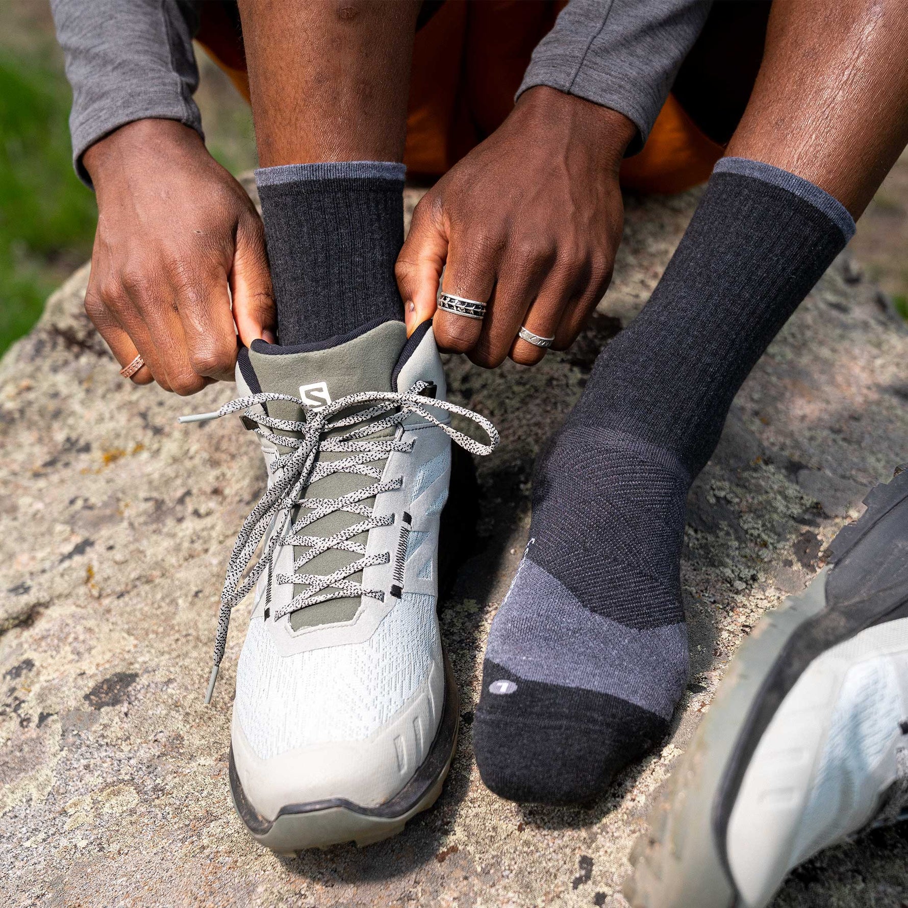 Person wearing charcoal gray Feetures Trail Max Cushion mini crew socks while tying running shoe