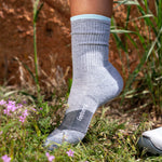 Feetures Trail Max Cushion Mini Crew sock in gray with blue accents on foot outdoors