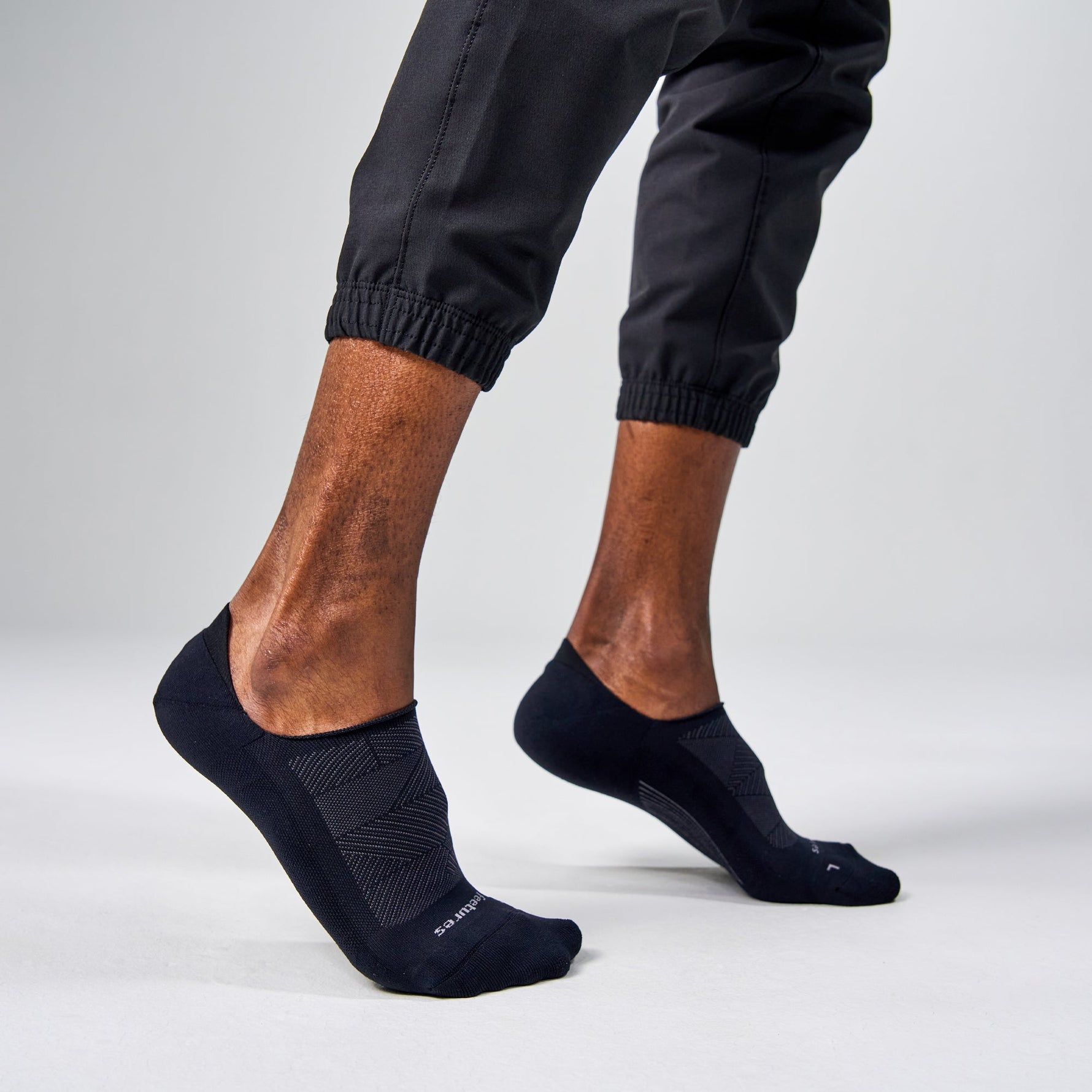 Feetures Elite Light Cushion Invisible black no-show socks worn by male model