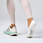 White Feetures Elite Light Cushion Invisible socks on model's feet with New Balance sneakers