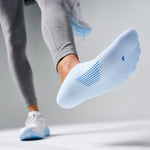 White Feetures Elite Light Cushion Invisible sock with blue stripes worn during exercise