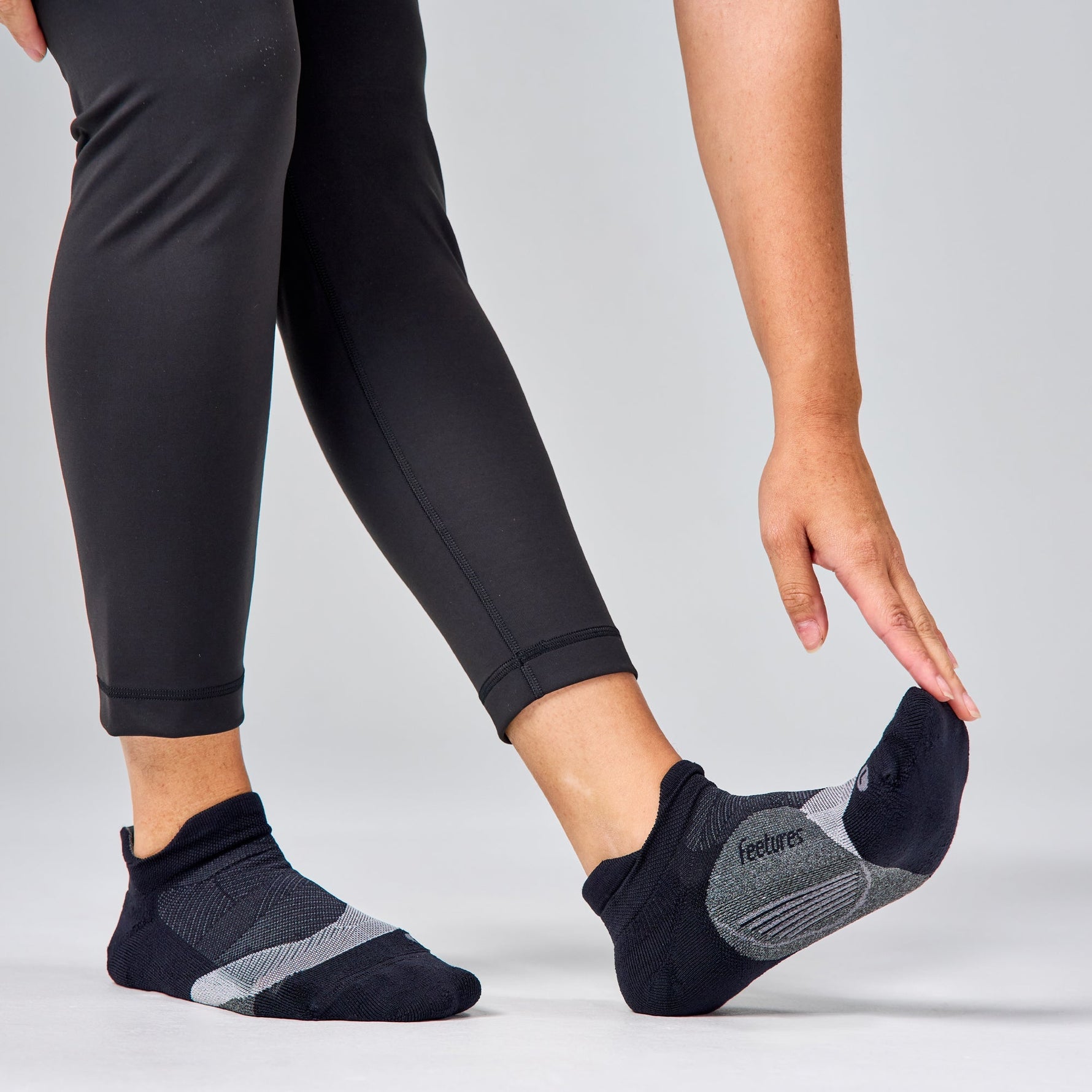 Feetures Elite Light Cushion Tab socks in black with gray pattern on model's feet