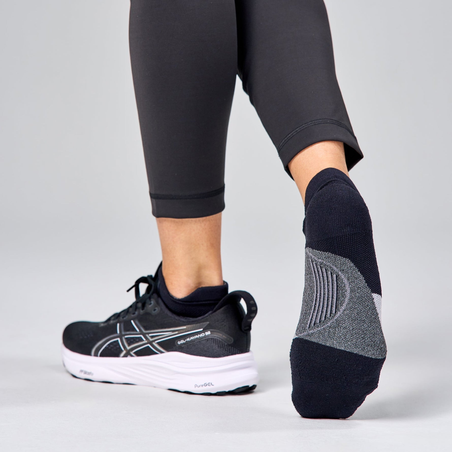 Feetures Elite Light Cushion Tab socks in navy and grey worn with running shoes