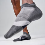 Person running wearing grey Feetures Elite Light Cushion Tab socks with brand label visible
