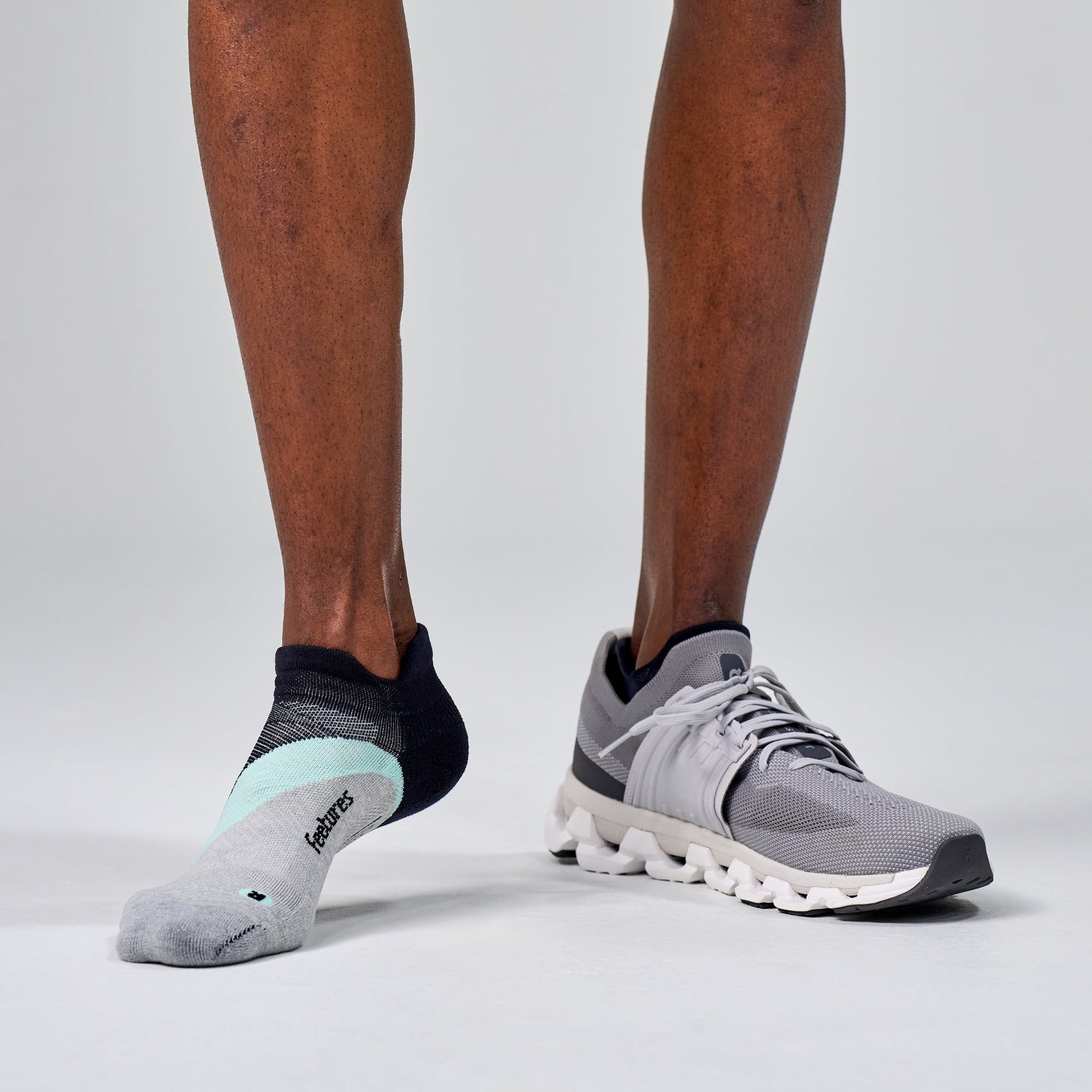 Feetures Elite Light Cushion Tab socks in navy and boost blue on runner's feet