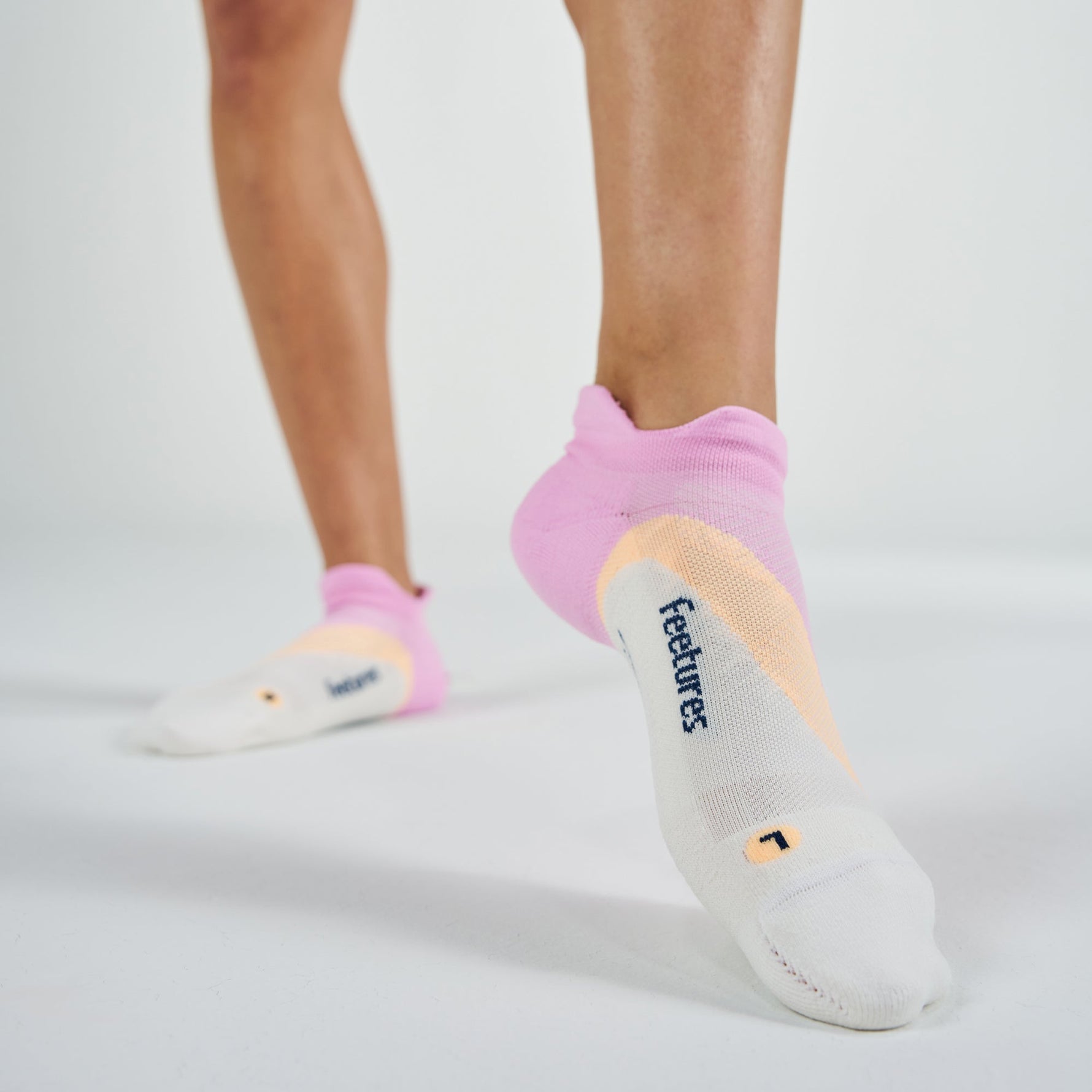 Person wearing pink Feetures Elite Light Cushion Tab no-show socks with brand logo