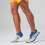 Feetures Elite Light Cushion Tab socks in grey with blue and orange accents on runner