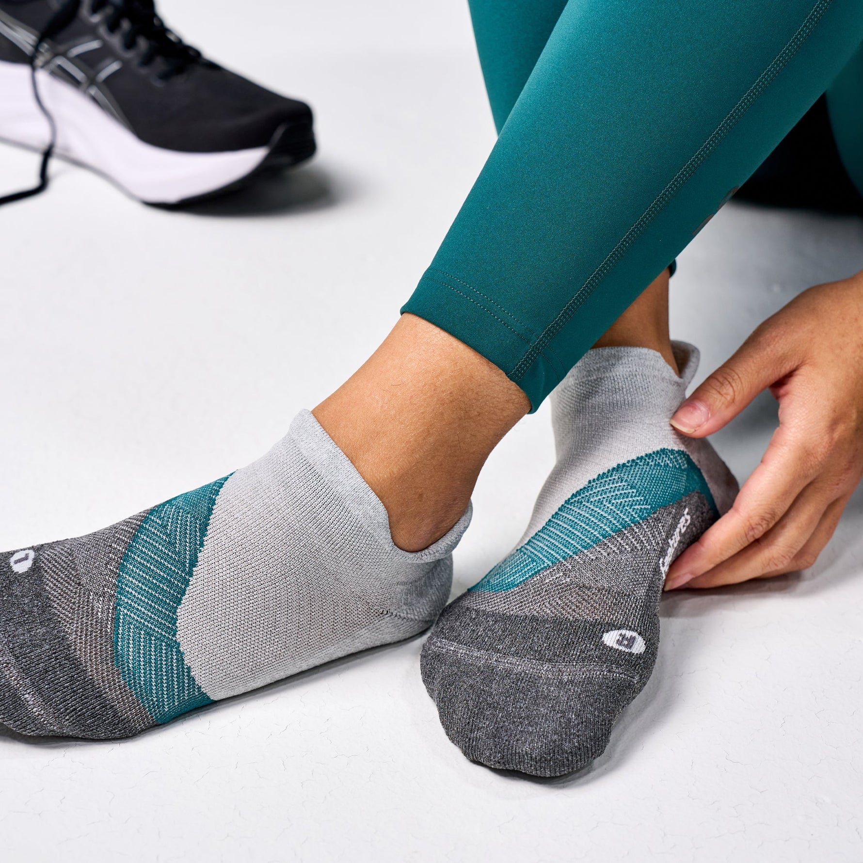 Grey Feetures Elite Light Cushion Tab socks with teal accents on feet