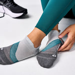 Feetures Elite Light Cushion Tab socks in gray with teal accents on feet
