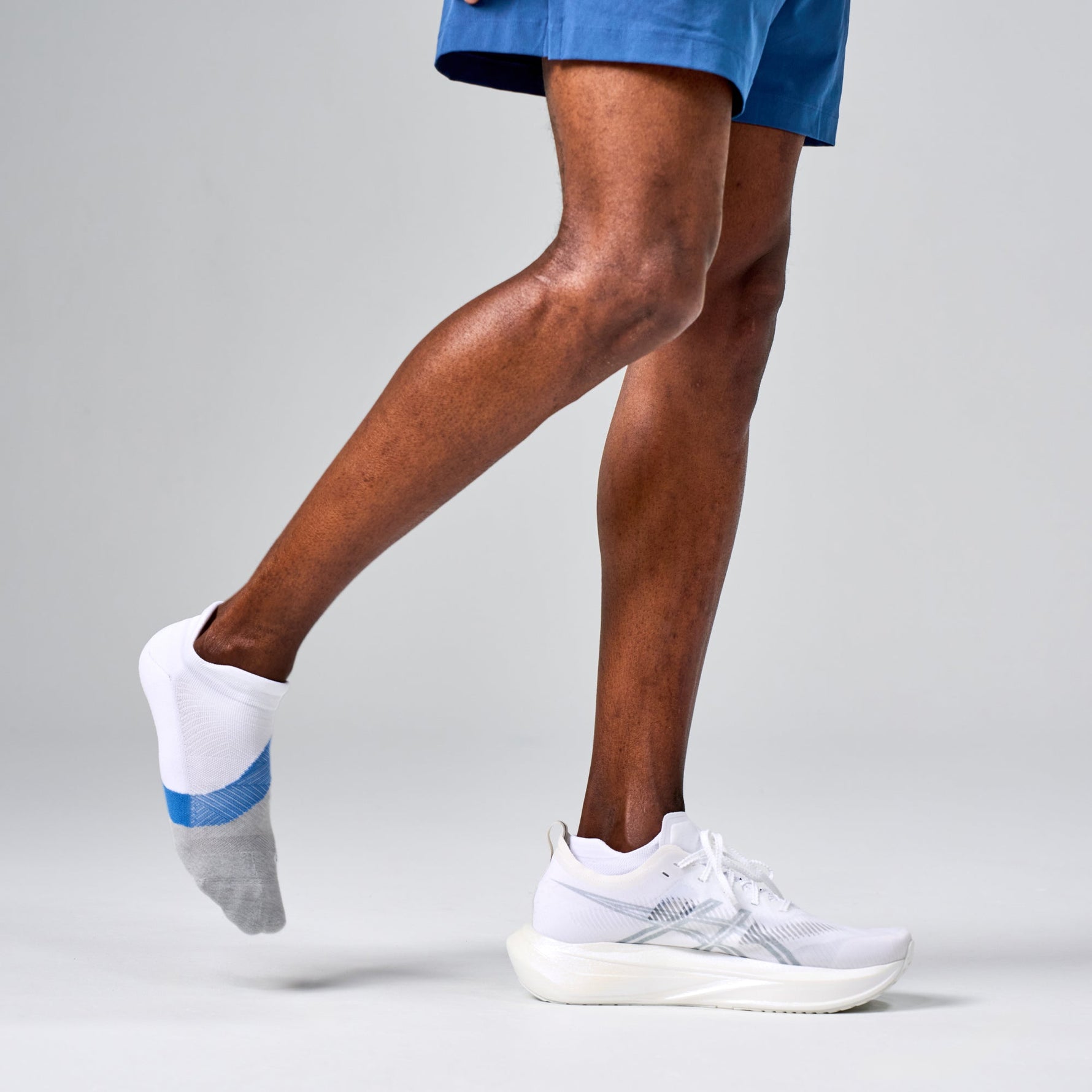 Feetures Elite Light Cushion Tab running socks in white with blue stripe on runner's feet