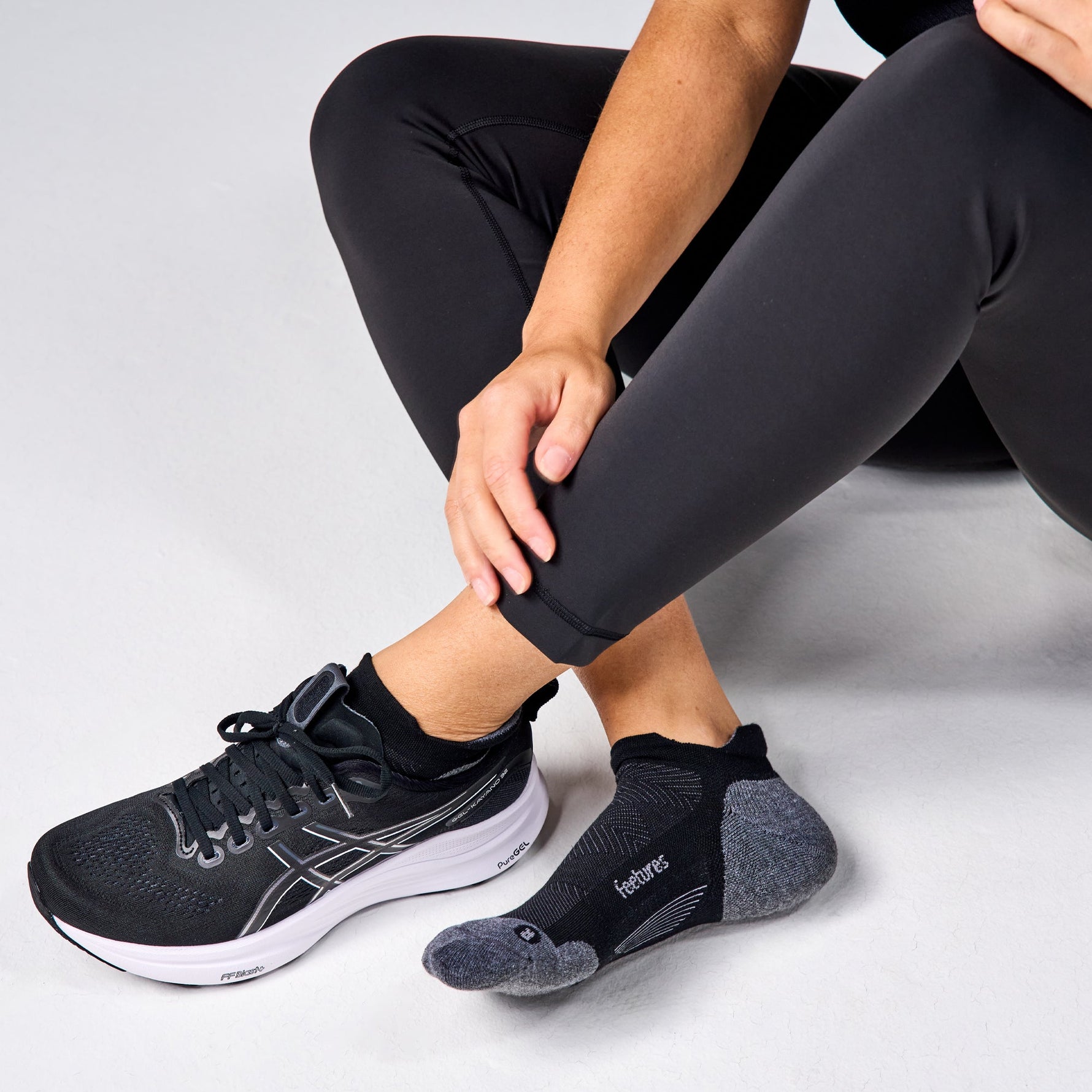 Person wearing black Feetures Elite Max Cushion Tab socks with running shoes