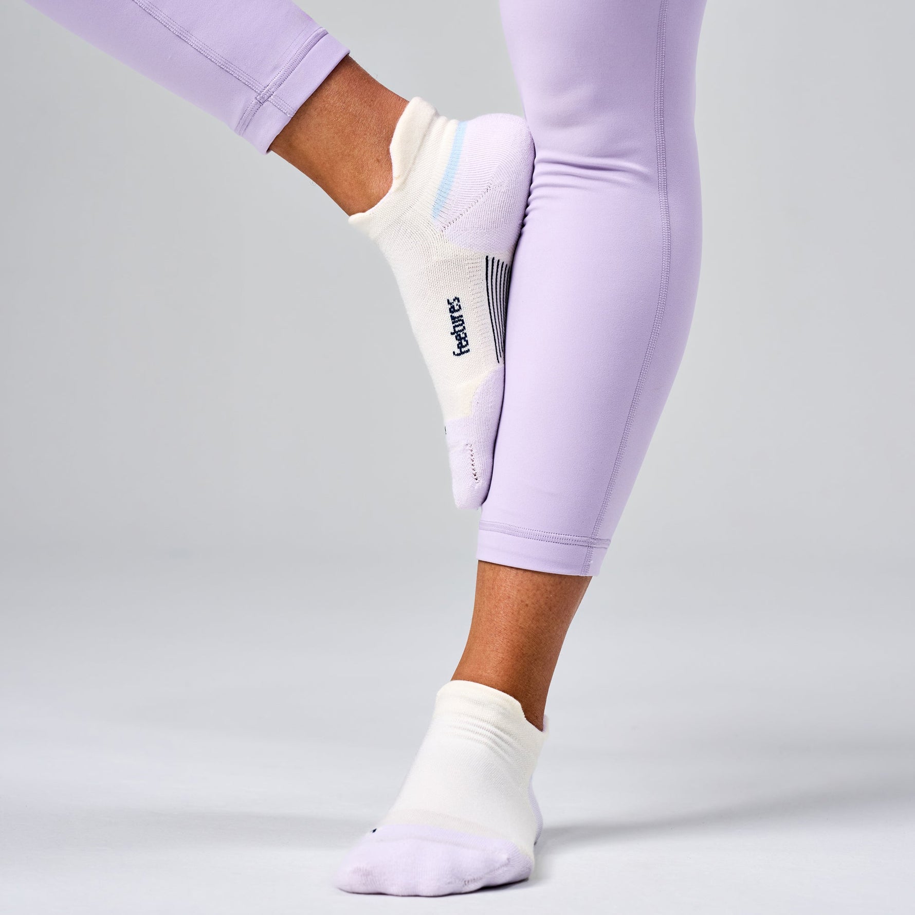 Feetures Elite Max Cushion Tab socks in white with purple accents on model's feet