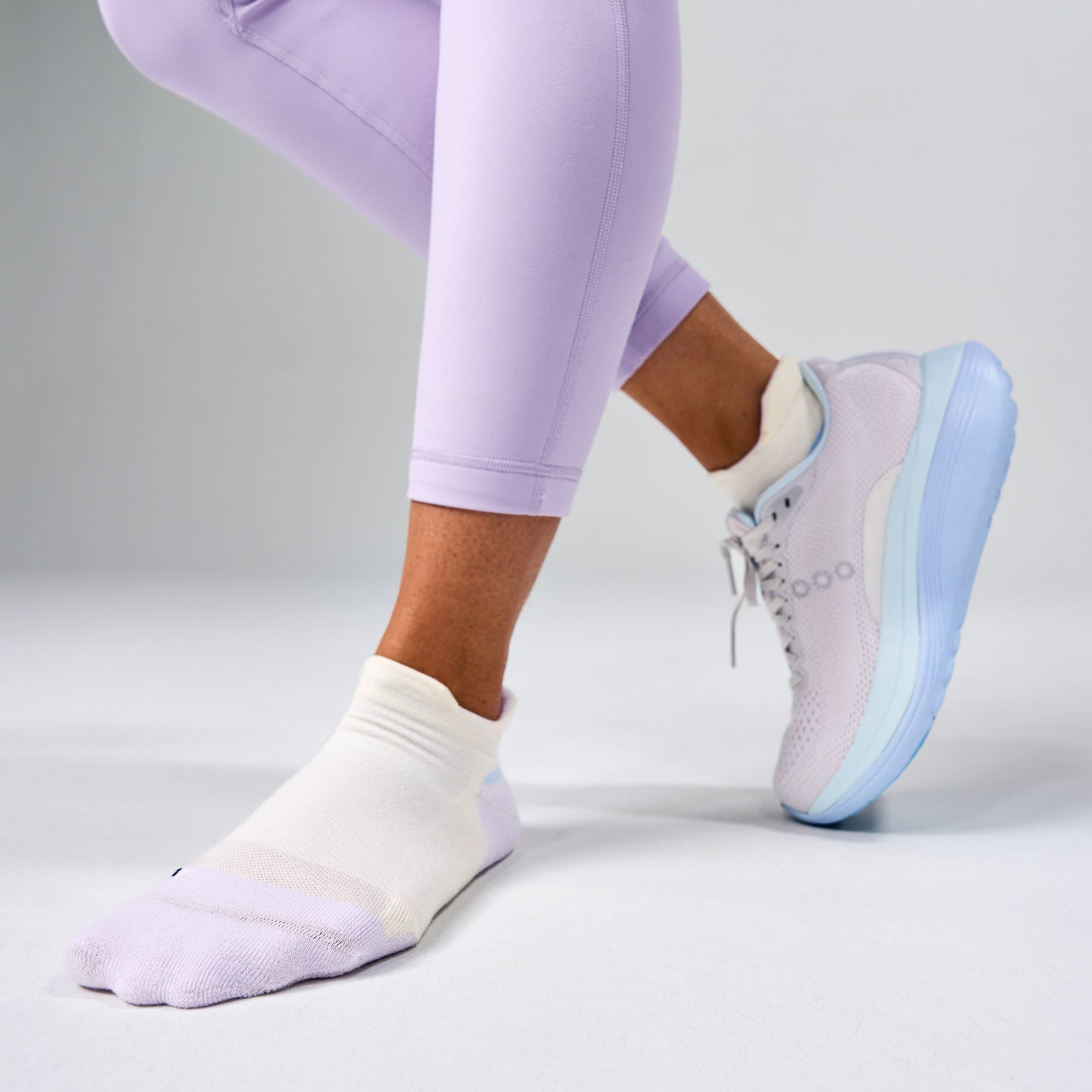 White Feetures Elite Max Cushion Tab socks worn with purple leggings and sneakers