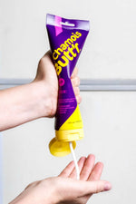Hands dispensing Chamois Butt'r HER anti-chafe cream from purple and yellow tube