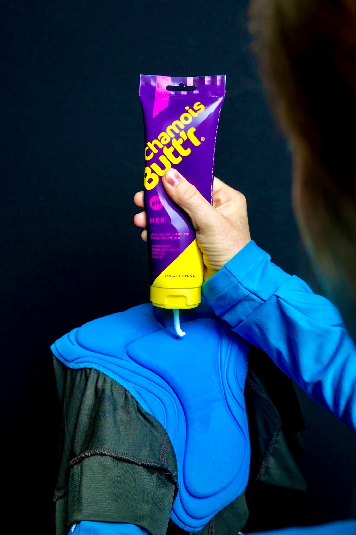 Hand holding Chamois Butt'r HER anti-chafe cream tube with purple packaging and yellow cap