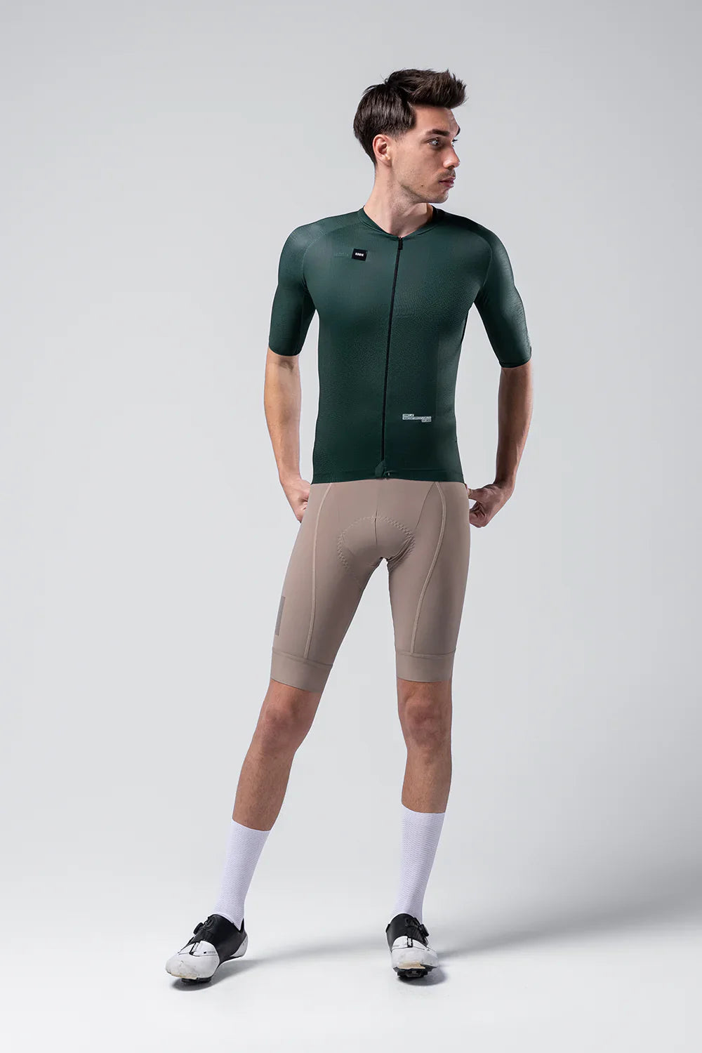 Male model wearing dark green Gobik cycling jersey with beige shorts in studio