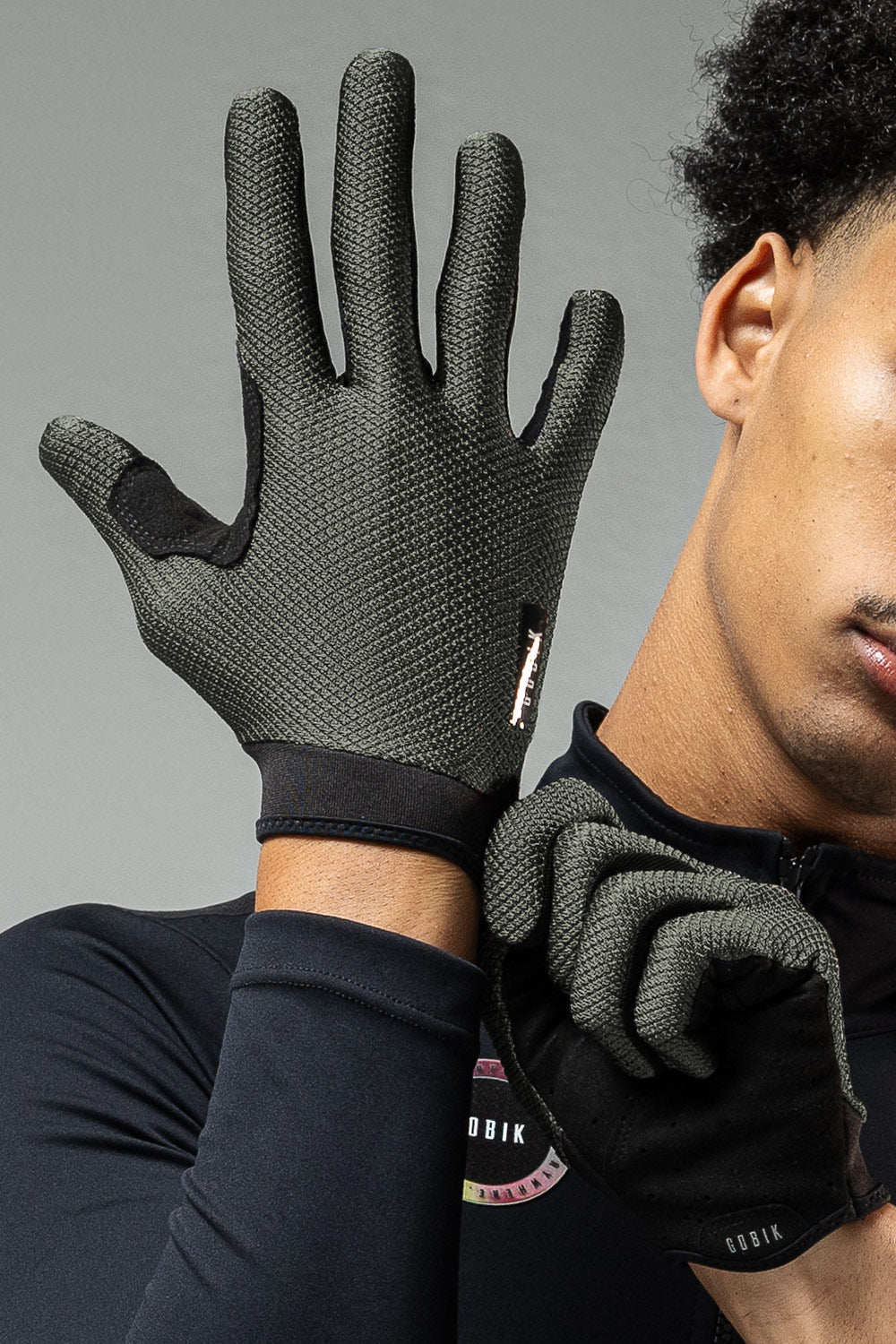 Model wearing GOBIK Lynx cycling gloves in army green with textured grip pattern