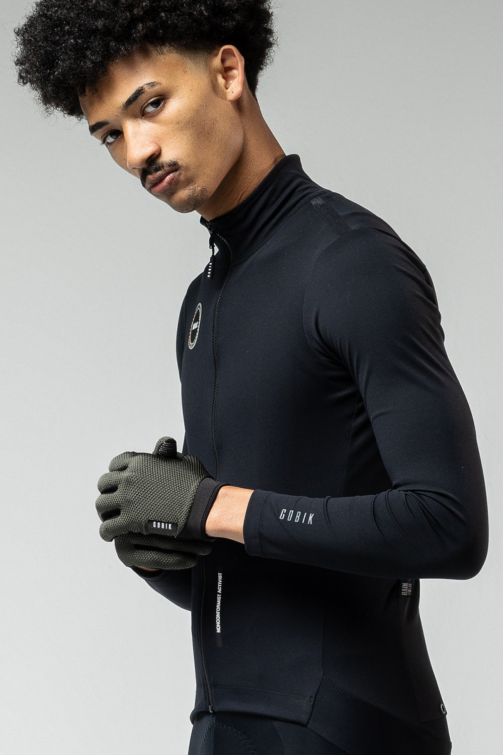 Model wearing olive green Gobik Lynx cycling gloves with black athletic jacket