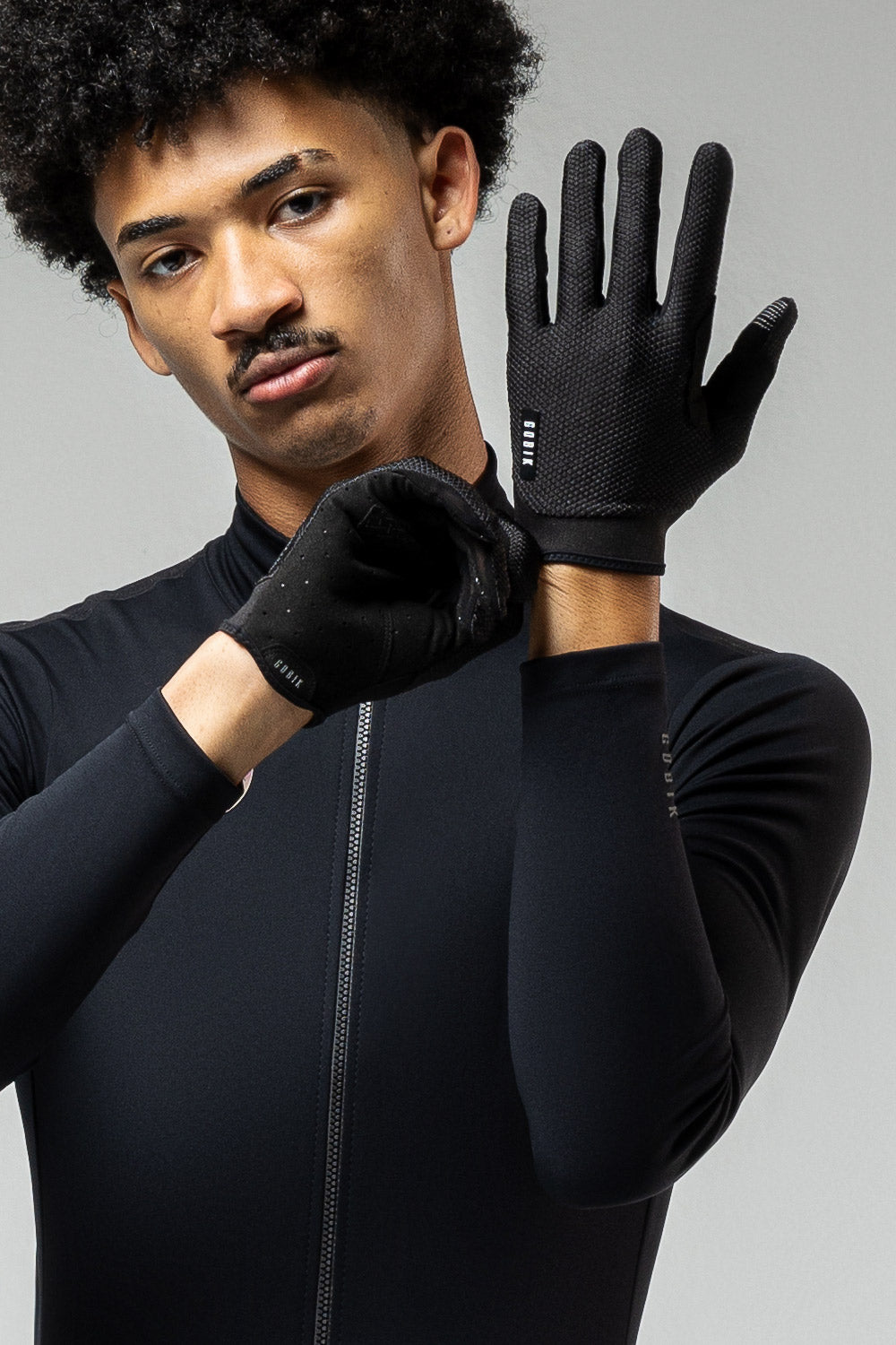 Model wearing black Gobik Lynx cycling gloves showing palm grip pattern and finger detail