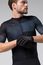 Man wearing black Gobik cycling gloves and matching jersey against neutral background