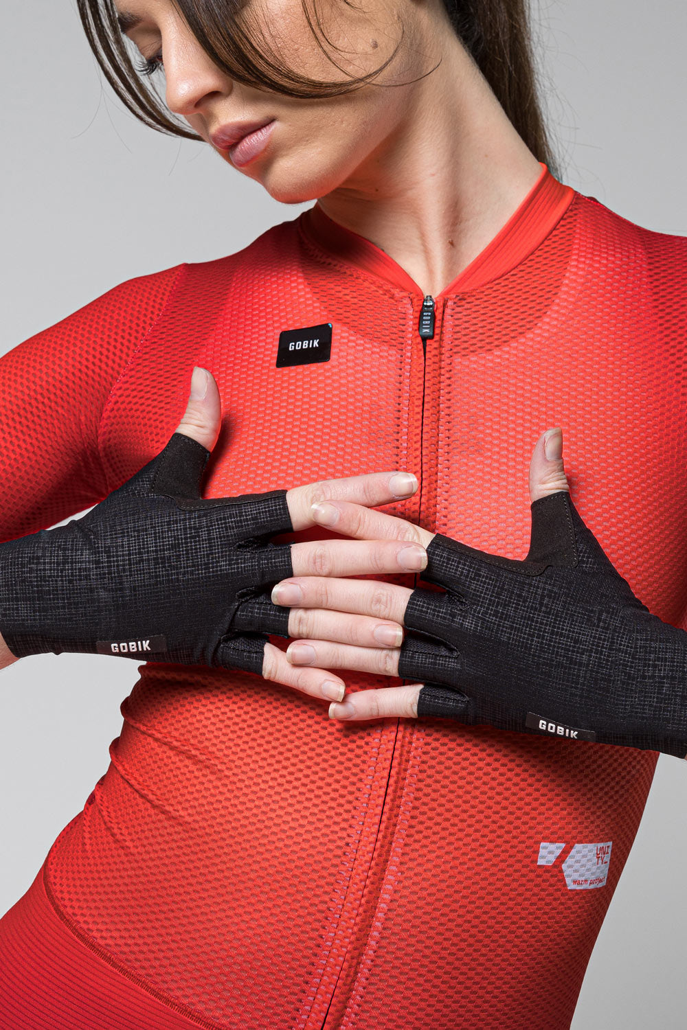 Black Gobik Mamba 2.0 fingerless cycling gloves worn by model in red jersey