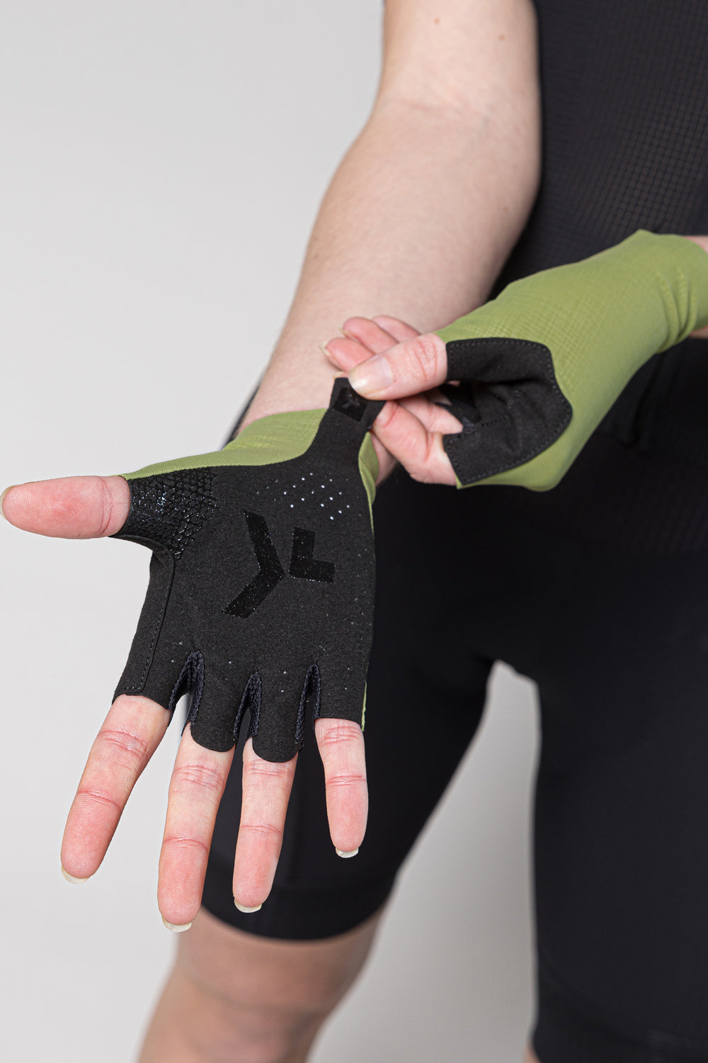 Person wearing black cycling gloves with olive green trim on fingers