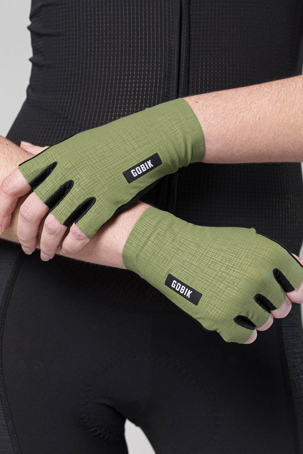 Gobik olive green cycling gloves with black branding worn on hands