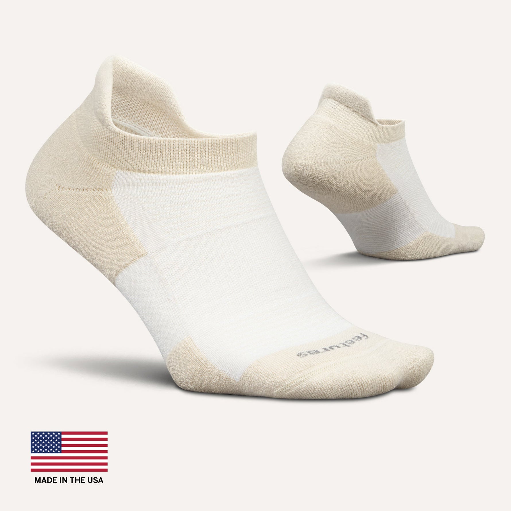 Feetures white performance tab socks with beige accents on clean background