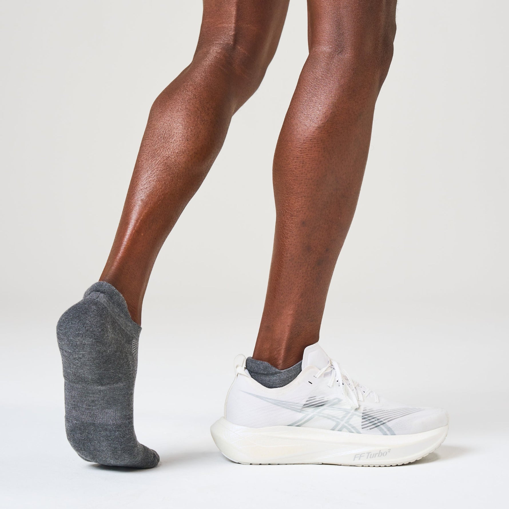 Person wearing heather grey Feetures tab socks with white athletic shoes