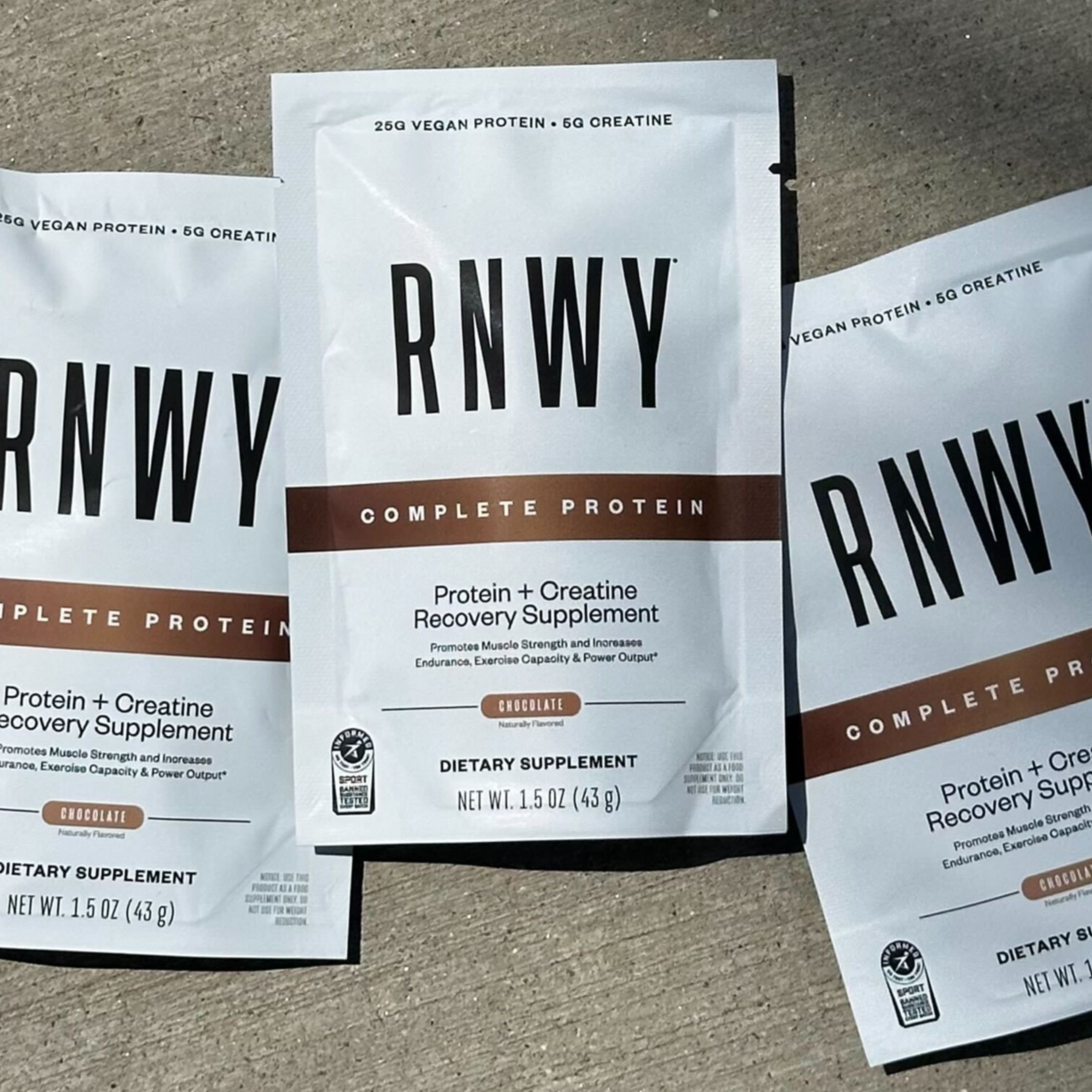 Three RNWY Complete Protein chocolate supplement packets with white and brown packaging design