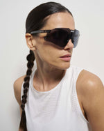 Woman wearing KOO Nebula sunglasses in Black Glass Photochromic Graphite Mirror on white background