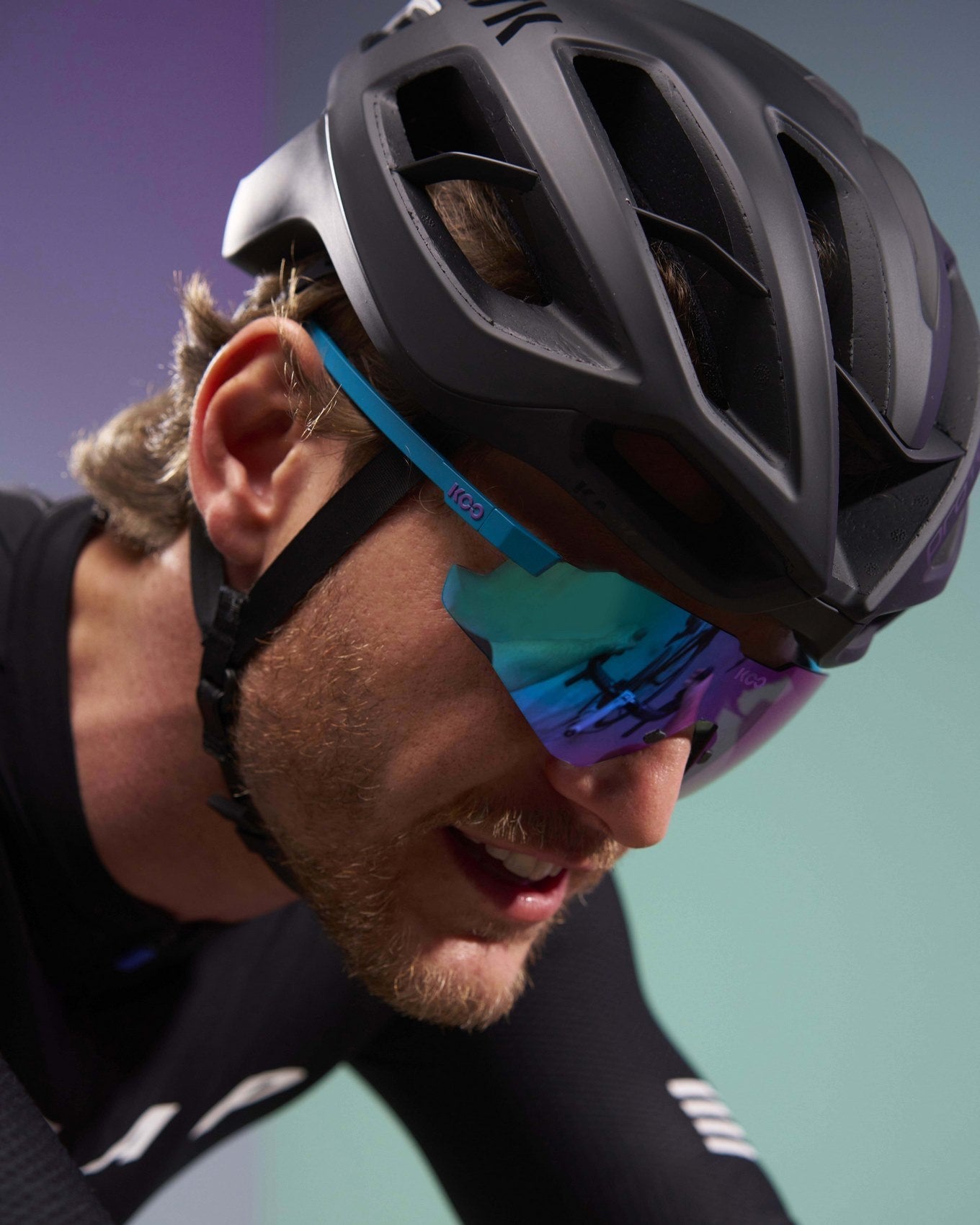 KOO Nebula cycling sunglasses in teal matt frame with dark turquoise mirror lens worn by cyclist