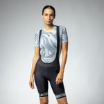 Woman wearing ALE PRR Strada black bibshorts with white details and gray patterned jersey