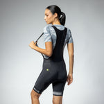 Woman wearing black ALE cycling bibshorts with white stripe details, studio photography