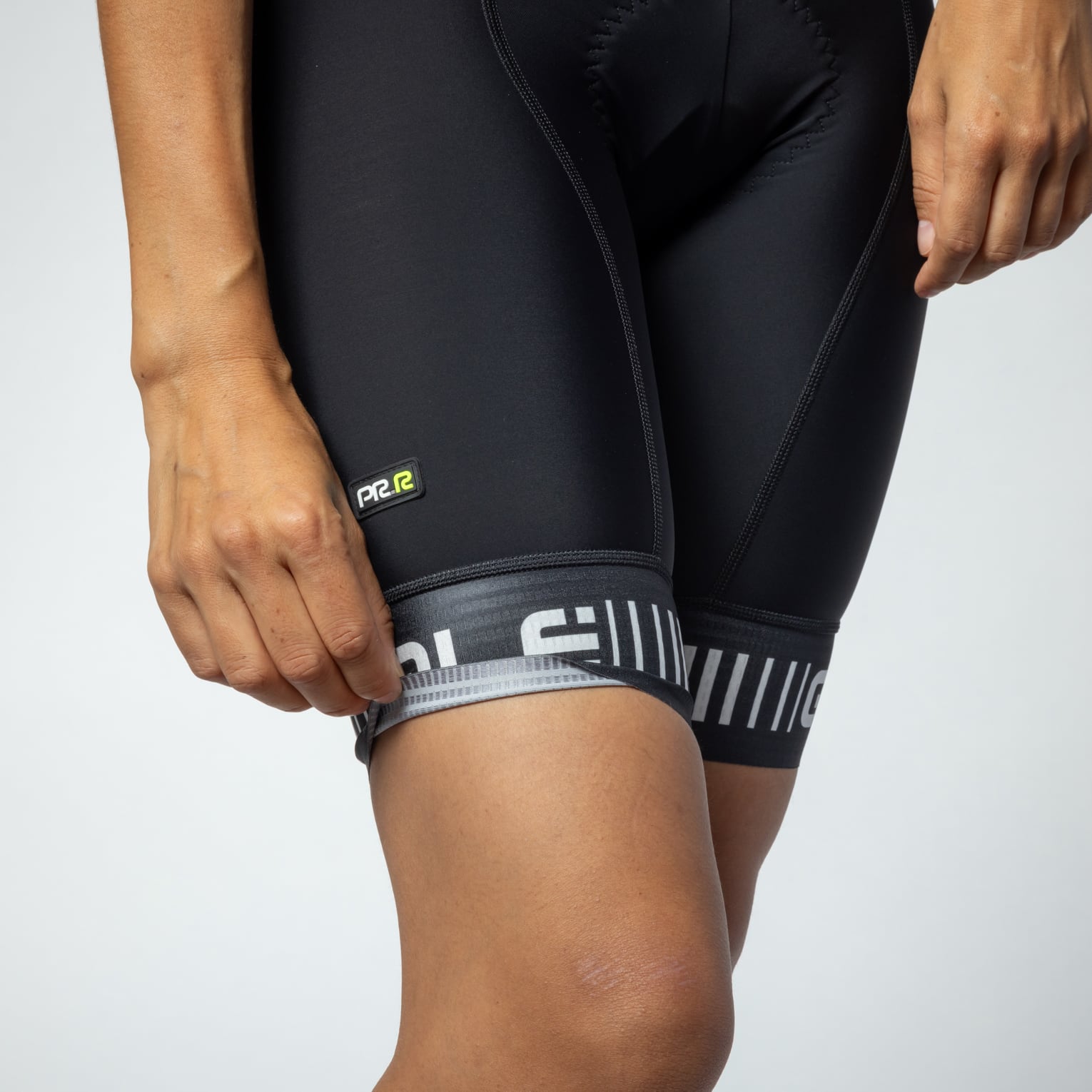 Close-up of black women's cycling bibshort leg with striped cuff and PRR logo