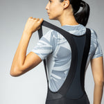 Woman wearing black ALE PRR Strada bibshorts with white leaf pattern shirt