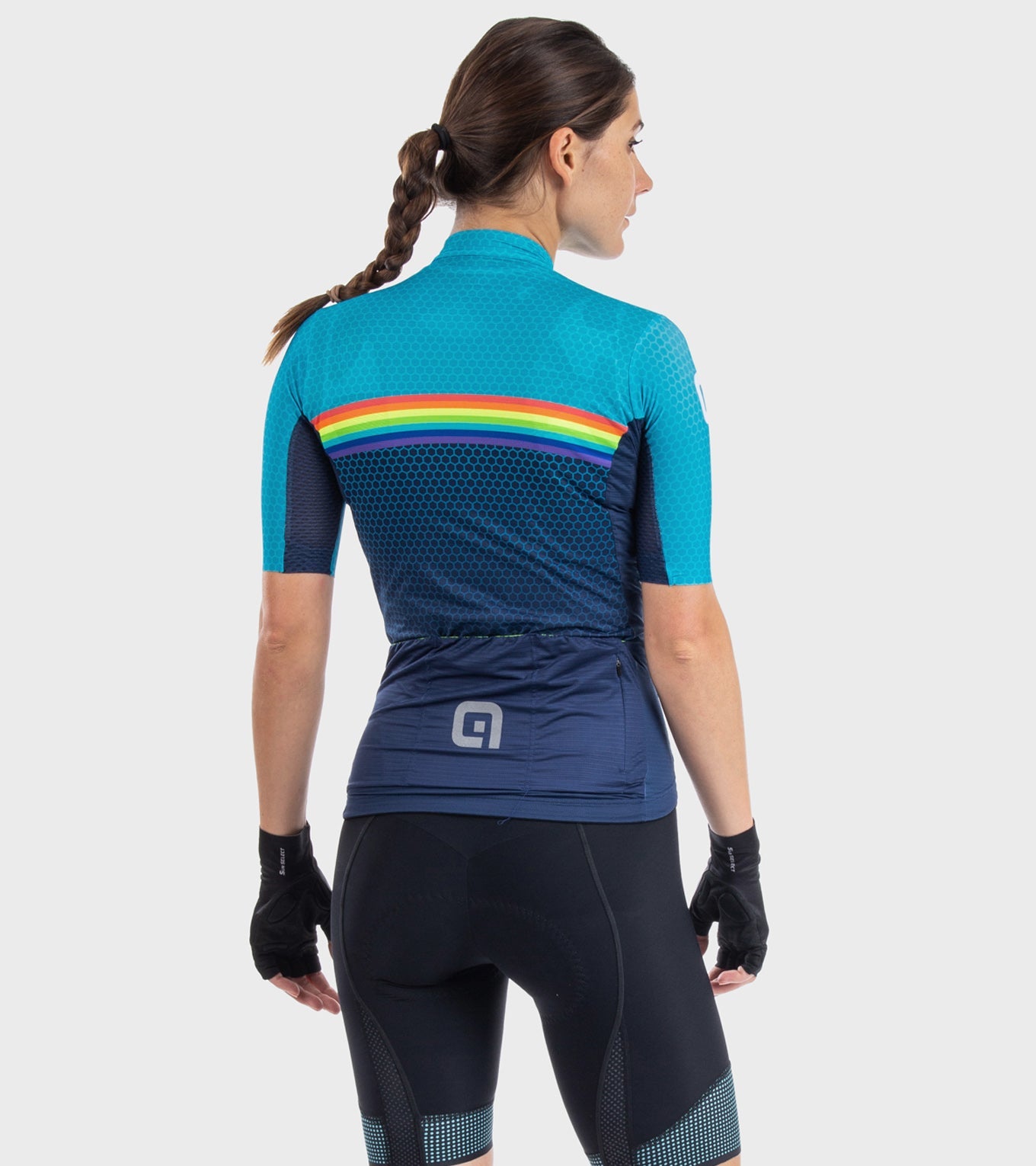 Woman wearing ALE cycling jersey with turquoise, navy, and rainbow stripe design