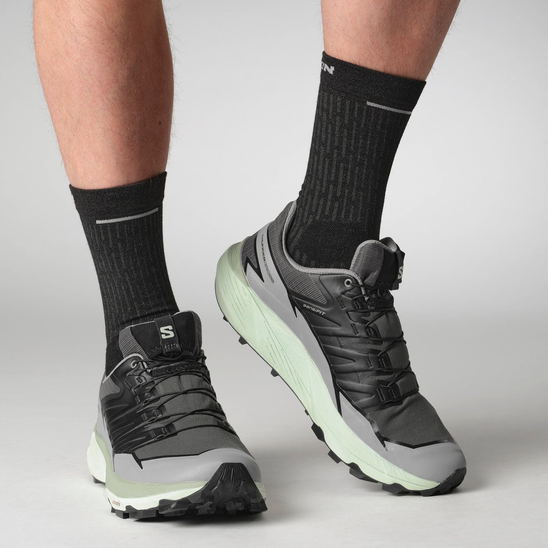 Salomon Thundercross trail running shoes in grey and charcoal colorway on model's feet