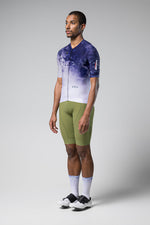 Male model wearing Gobik CX Pro cycling jersey in blue gradient pattern with green shorts