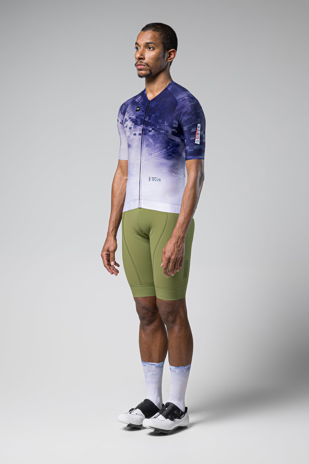 Male model wearing Gobik CX Pro cycling jersey in blue gradient pattern with green shorts