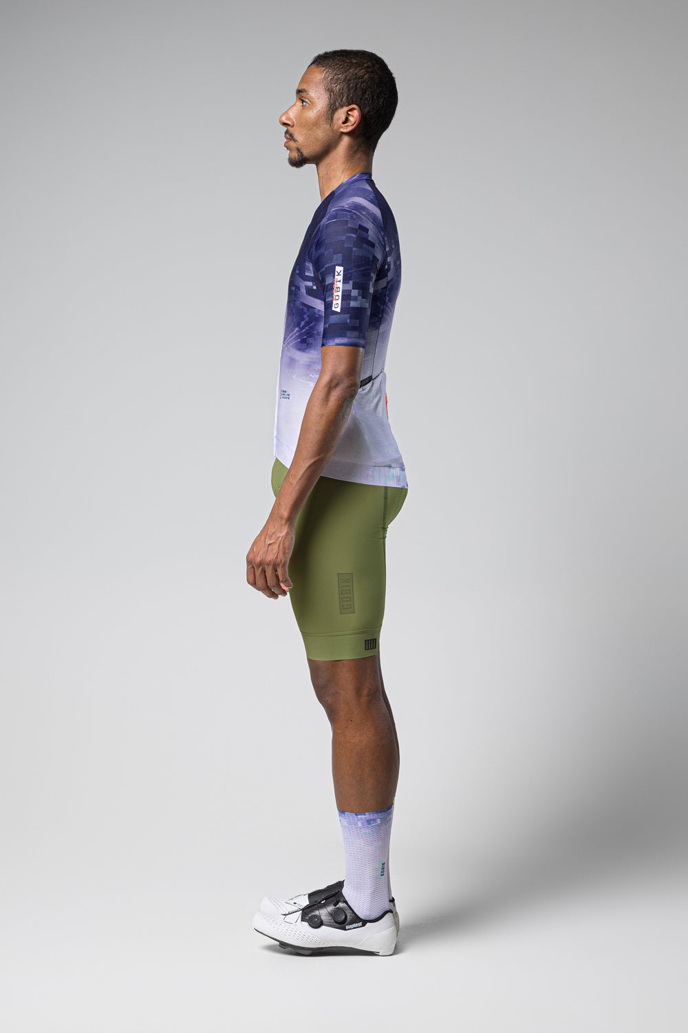 Male model wearing Gobik CX Pro jersey in blue gradient pattern with green cycling shorts