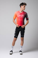 Male cyclist wearing Gobik INEOS Grenadiers red gradient cycling jersey with black shorts